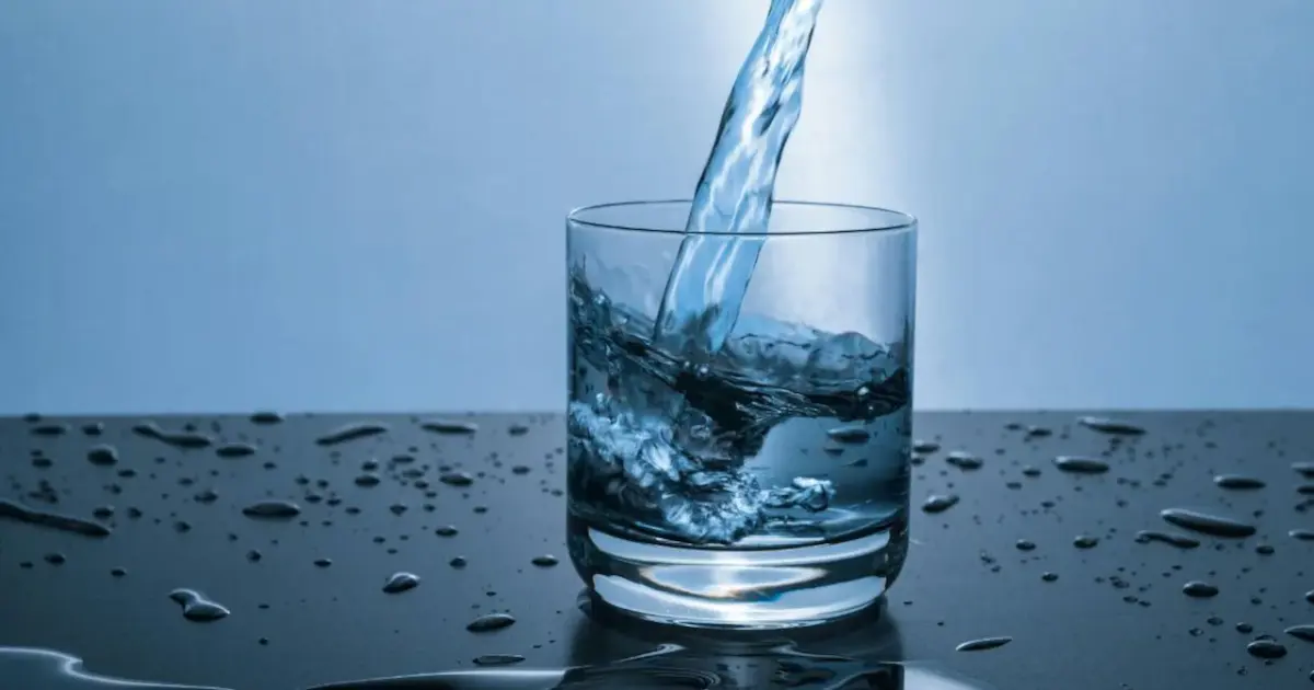 Various fresh ingredients like lemon, cucumber, mint, and berries arranged around a glass of water, symbolizing enhanced hydration.