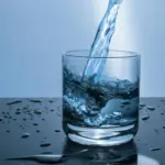Various fresh ingredients like lemon, cucumber, mint, and berries arranged around a glass of water, symbolizing enhanced hydration.