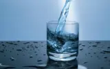 Various fresh ingredients like lemon, cucumber, mint, and berries arranged around a glass of water, symbolizing enhanced hydration.