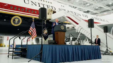 Donald Trump standing next to the Qatar-gifted Air Force One, a luxurious presidential aircraft.