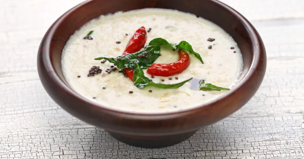 Close-up of a bowl of coconut chutney with a spoon, highlighting its texture and ingredients.