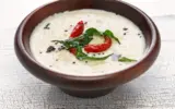 Close-up of a bowl of coconut chutney with a spoon, highlighting its texture and ingredients.