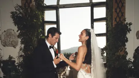 Dua Lipa and Callum Turner smiling at their Italian wedding ceremony.