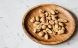 A person carefully placing airtight containers filled with peanuts into a cool, dark pantry.