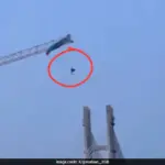 Paraglider tangled on a tower crane in China, dangling precariously.