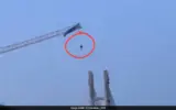 Paraglider tangled on a tower crane in China, dangling precariously.