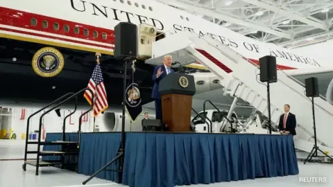 Donald Trump standing next to the Qatar-gifted Air Force One, a luxurious presidential aircraft.