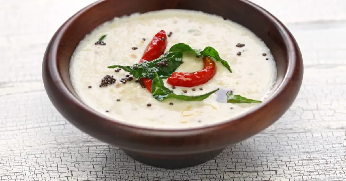 Close-up of a bowl of coconut chutney with a spoon, highlighting its texture and ingredients.