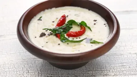 Close-up of a bowl of coconut chutney with a spoon, highlighting its texture and ingredients.