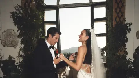 Dua Lipa and Callum Turner smiling at their Italian wedding ceremony.