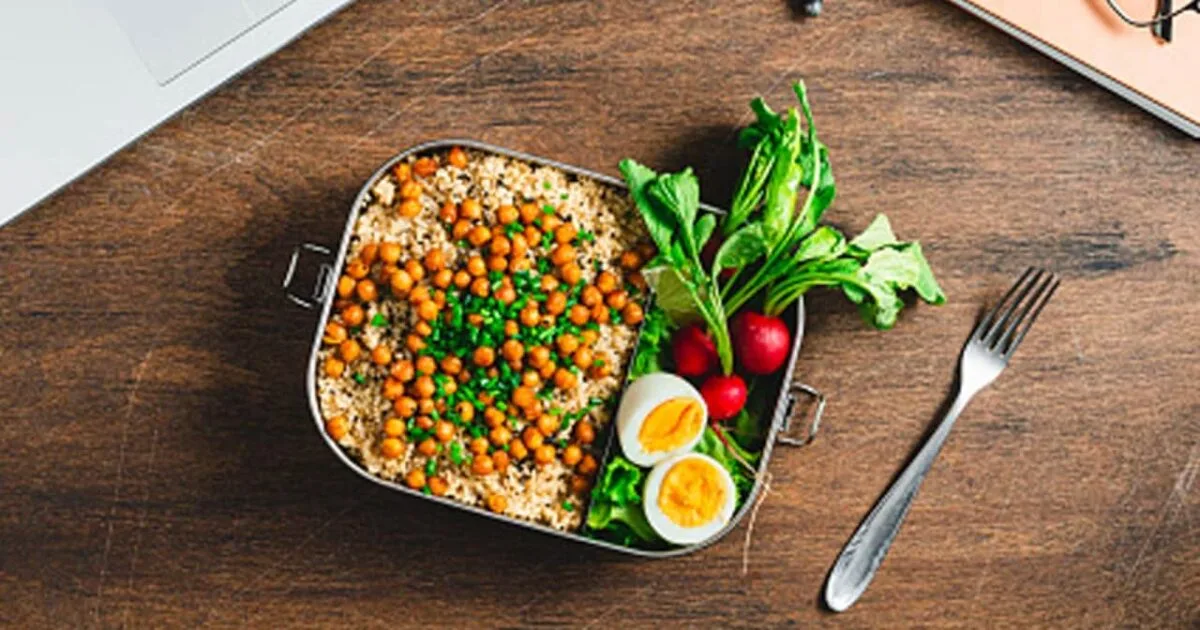 Person packing a healthy and safe lunchbox with fresh ingredients, illustrating packed lunch safety tips.
