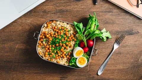 Person packing a healthy and safe lunchbox with fresh ingredients, illustrating packed lunch safety tips.
