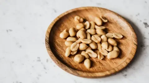 A person carefully placing airtight containers filled with peanuts into a cool, dark pantry.