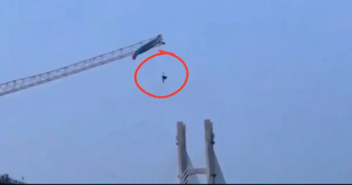 Paraglider tangled on a tower crane in China, dangling precariously.