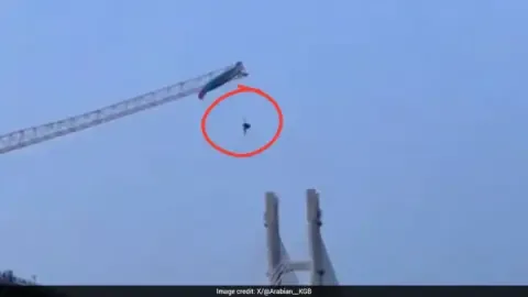 Paraglider tangled on a tower crane in China, dangling precariously.