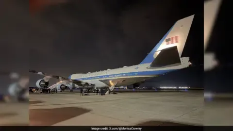 Air Force One aircraft on the tarmac with a Qatari jet in the background.