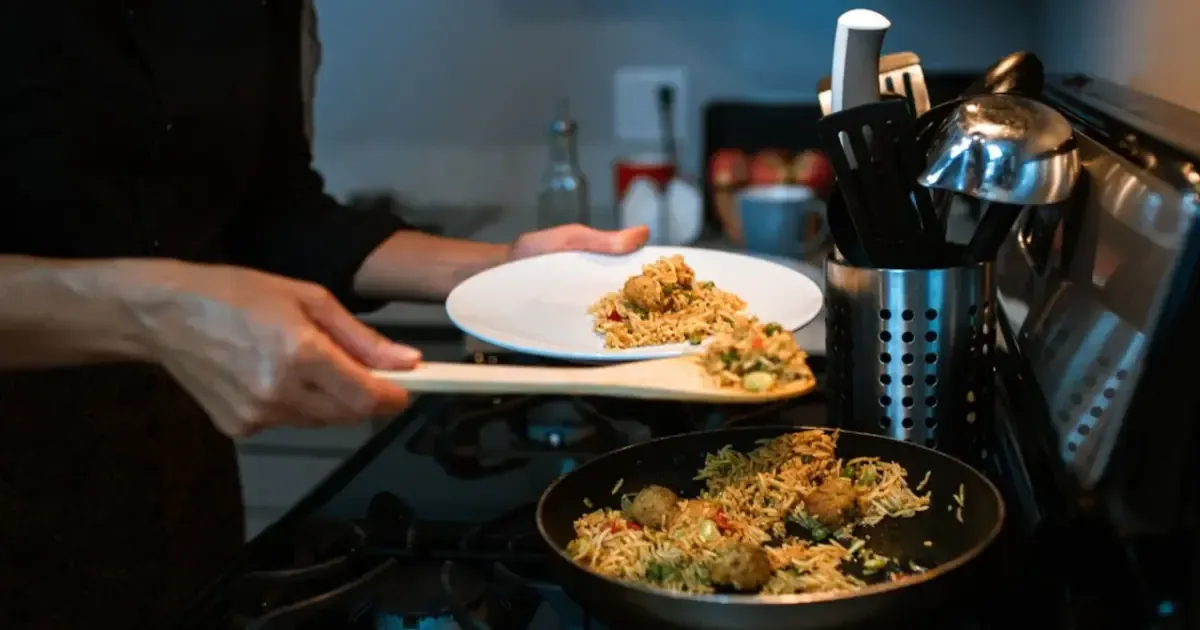 Person carefully reheating food in a microwave, illustrating safe reheating practices for leftovers.