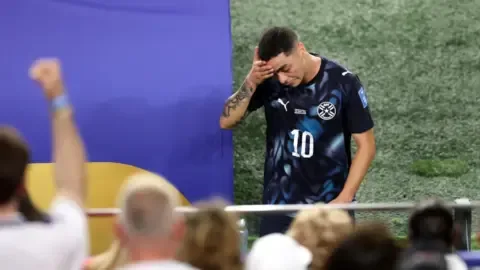 Miguel Almiron receives a red card for covering his mouth during a football match.