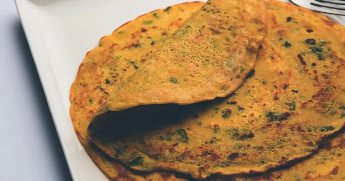 A perfectly cooked besan chilla being flipped without breaking, showcasing its golden-brown texture.