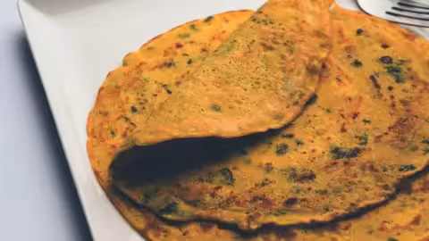 A perfectly cooked besan chilla being flipped without breaking, showcasing its golden-brown texture.