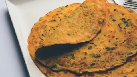 A perfectly cooked besan chilla being flipped without breaking, showcasing its golden-brown texture.